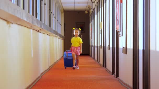 A little girl is walking around the hotel with a childrens suitcase. — Stockvideo