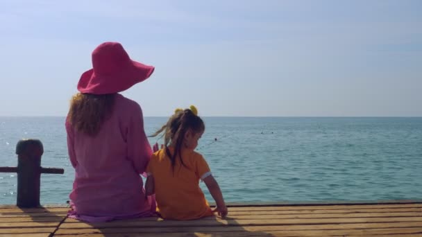 Moeder en dochter wandelen langs de pier aan de kust en bewonderen de zee. — Stockvideo