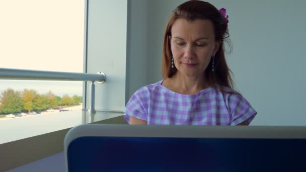 La fille travaille sur un ordinateur portable sur le balcon de l'hôtel . — Video