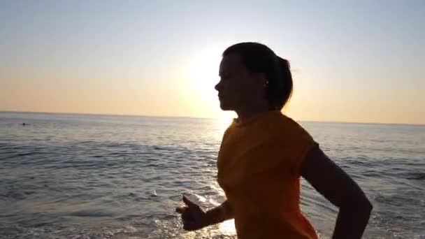 Mladá žena jogging podél písečné mořské pláže.