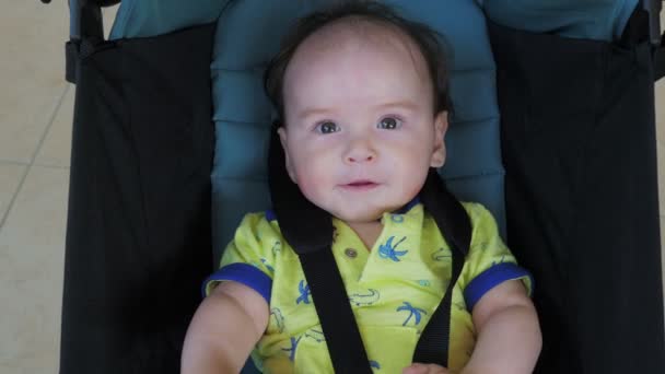 Klein lachend jongetje zit in een kinderwagen en lacht. — Stockvideo