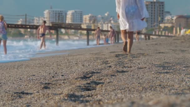 Żeńskie nogi spacerują wzdłuż piaszczystej plaży kurortowej. — Wideo stockowe