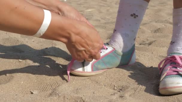 Moeder bindt de veters op haar dochters sneakers close-up. — Stockvideo