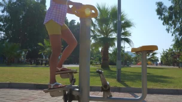 A young woman is training on a street trainer. — Stock Video