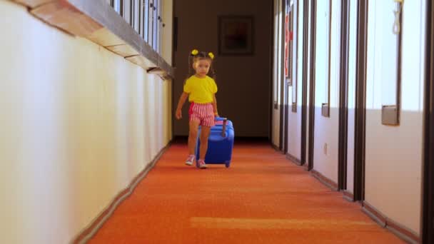 Een klein meisje loopt rond in het hotel met een kinderkoffer.. — Stockvideo