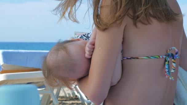 Mamma tiene tra le braccia e culla il bambino, essendo sulla spiaggia del mare . — Video Stock