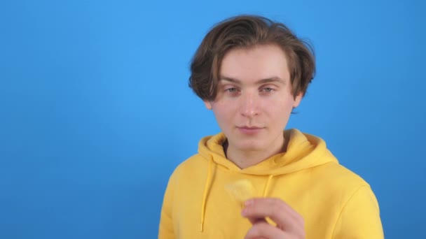 Veselý chlap jíst bramborové lupínky na modrém pozadí — Stock video