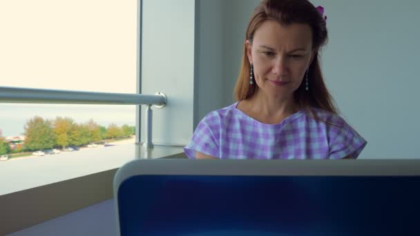 La fille travaille sur un ordinateur portable sur le balcon de l'hôtel . — Video
