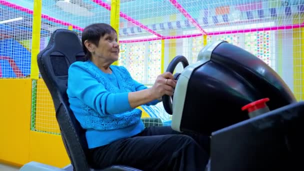 Wanita senior bersenang-senang sambil mengendarai simulator mobil — Stok Video