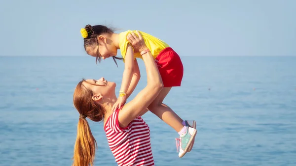 Cheerful young mom and daughter having fun on beach in summer — Stock Photo, Image