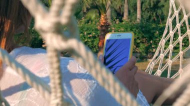 Yazın bahçede akıllı telefon kullanan neşeli bir kadın.