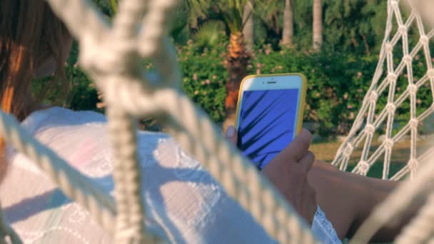 Cheerful woman using smartphone in garden in summer — Stock Video