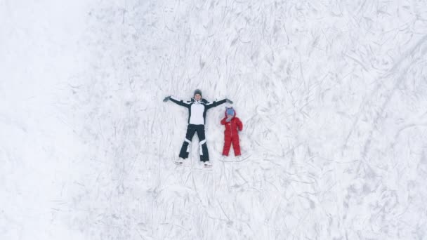 Mujer y niño acostados en el hielo en la pista de patinaje — Vídeo de stock