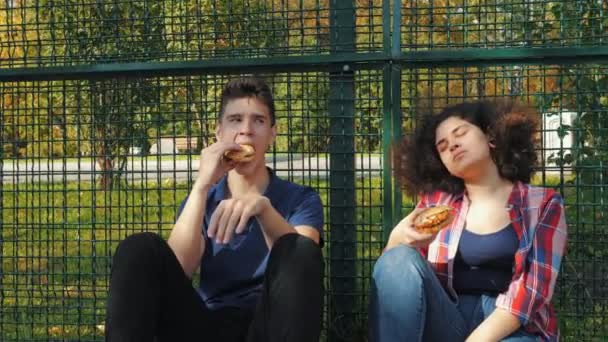 Vrienden die hamburgers eten op sportterrein — Stockvideo