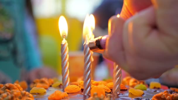 Анонімний хлопець запалює свічки на святковому торті — стокове відео