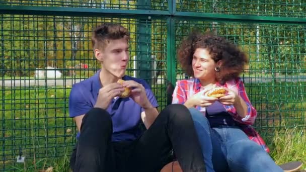Amigos comendo hambúrgueres em campo esportivo — Vídeo de Stock