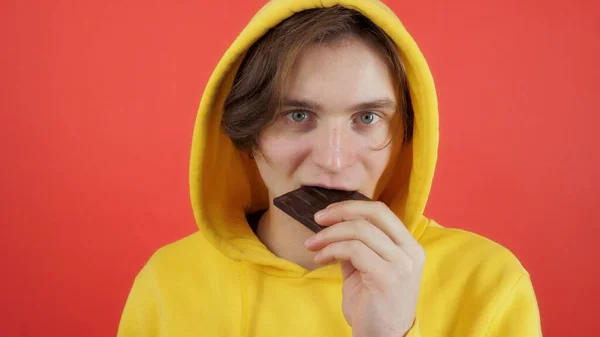 Genç adam tatlı çikolata yiyor.