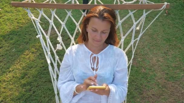 Wesoła kobieta korzystająca ze smartfona w ogrodzie latem — Wideo stockowe