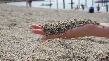Female hand with small pebble on beach