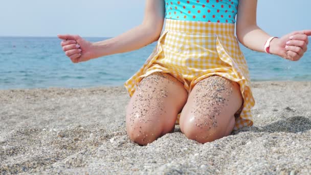 Anónimo señora en reposo con arena de guijarros en las piernas y en las manos en la orilla del mar — Vídeo de stock