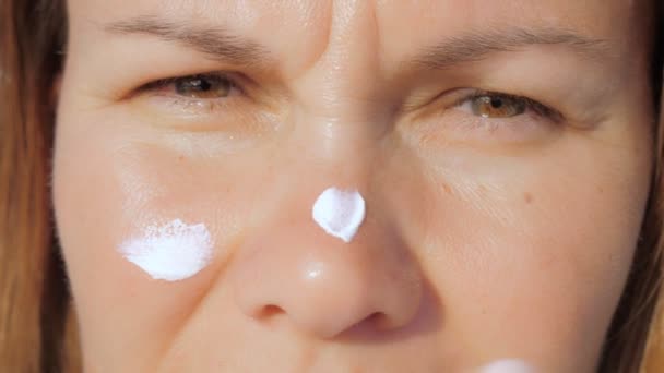 Meisje smeert haar gezicht huid met sunblock crème terwijl staan op een strand — Stockvideo