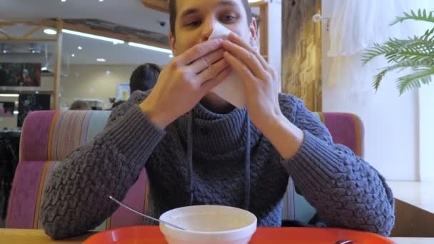 Fornøyd ung mann nyter lunsj på kafeen – stockvideo