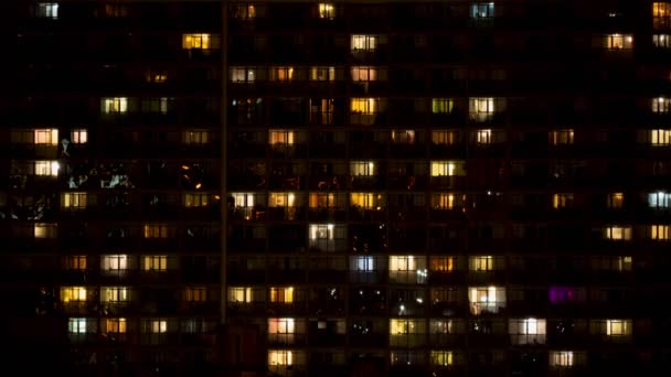 Caducidad nocturna de luz en las ventanas de un edificio de varios pisos — Vídeos de Stock