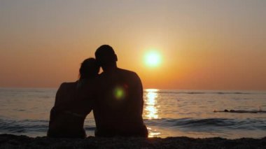 Renkli bir gün batımını izleyen bir adamla bir kadın..