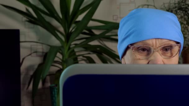 An elderly woman with glasses uses a laptop. — 图库视频影像