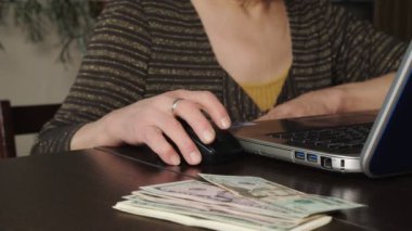 Yaşlı bir kadın internette para kazanmak için dizüstü bilgisayar kullanıyor..