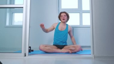 Genç adam evde yoga yapıyor.