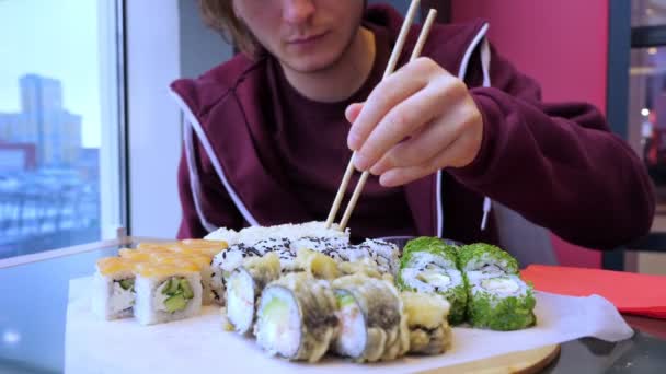 Crop young man eating sushi in restaurant — Stock Video