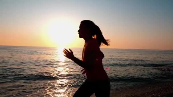 Een jonge vrouw joggen langs het zandstrand. — Stockvideo