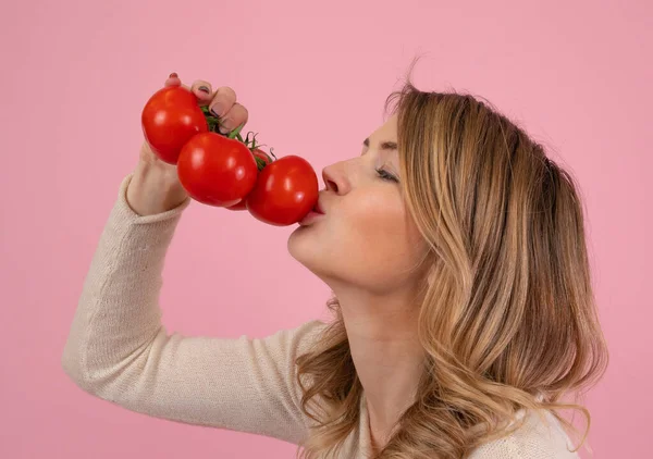 Modern kadın olgun domatesleri öpüyor.