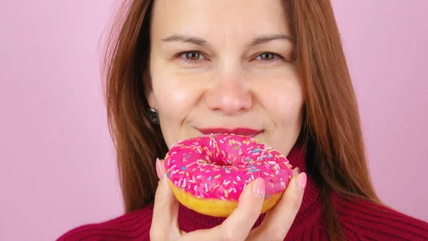 Yetişkin bir kadın lezzetli çörekleri ısırıyor.