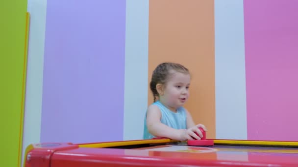 Маленькая девочка играет в воздушный хоккей — стоковое видео