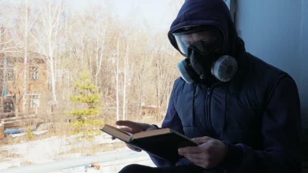 Man in gas mask reading book in destroyed building — Stock Video