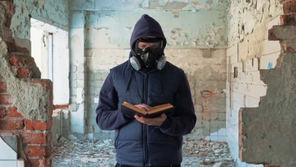 Mann mit Gasmaske liest Buch in zerstörtem Gebäude — Stockvideo
