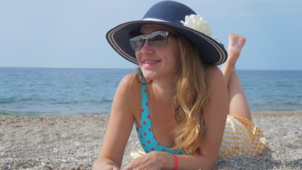 Turista feminino positivo em óculos de sol e chapéu na praia do mar — Vídeo de Stock