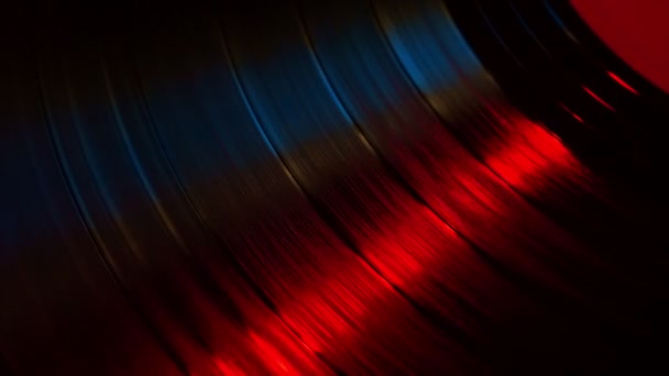 Fragment d'un disque vinyle rotatif dans les rayons rouges d'une discothèque 