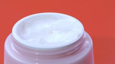 Kadın pembe kavanozdan parmak kremi alıyor. Kapat.