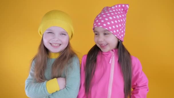 Dos niñas lindas alegres que se divierten sobre un fondo amarillo — Vídeos de Stock