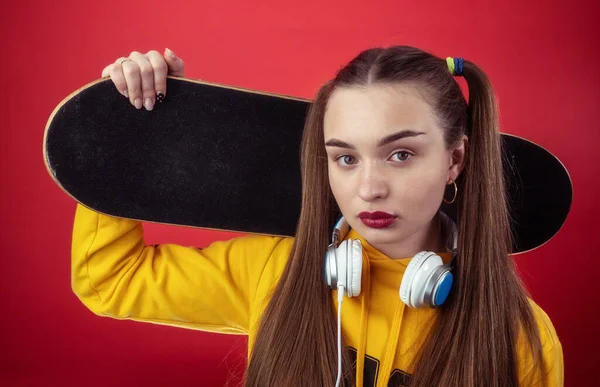 Kulaklıklı ve kaykaylı genç bir kadın.