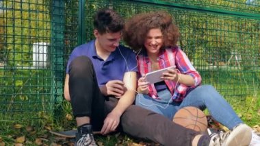 Sokakta arkadaşlarıyla tablet izleyen genç bir kadın.