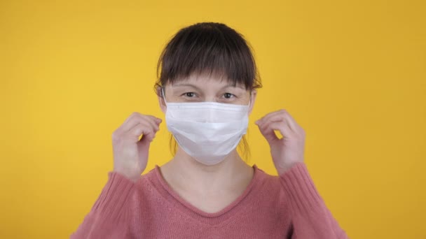 Joyful vrouw neemt een medisch masker af op een gele achtergrond — Stockvideo