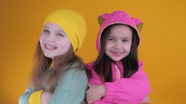 Two cheerful cute little girls having fun on a yellow background — Stock Video