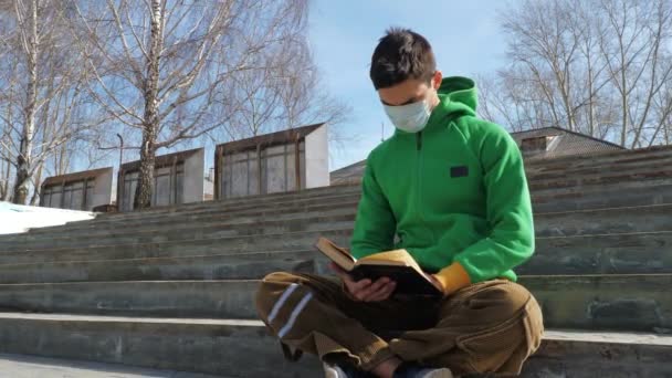 Joven leyendo libro en la calle durante epidemia — Vídeos de Stock