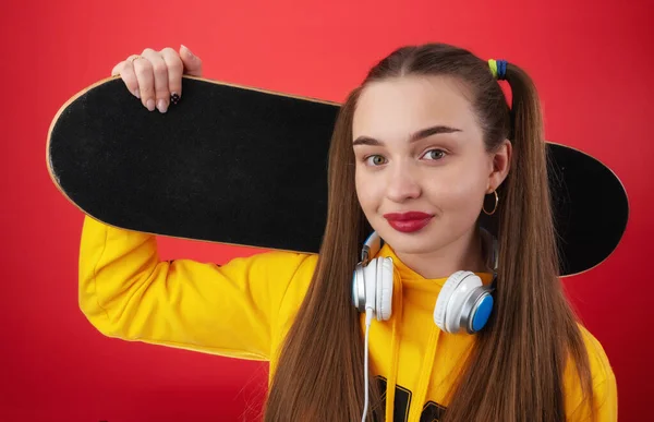 Kulaklıklı ve kaykaylı genç bir kadın.