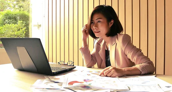 Businesswoman busy with job stress greatly at office desk working with laptop computer overwhelmed by paperwork workload covering her face.