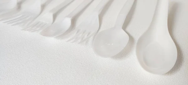 Beyaz arka planda beyaz plastik kaşık ve çatal.